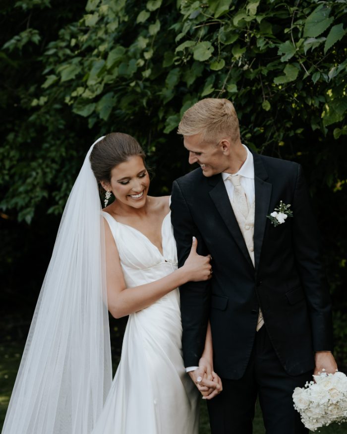 Bride and groom holding hands under greenery